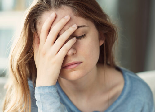 Photo of an upset woman covering her face with her hand